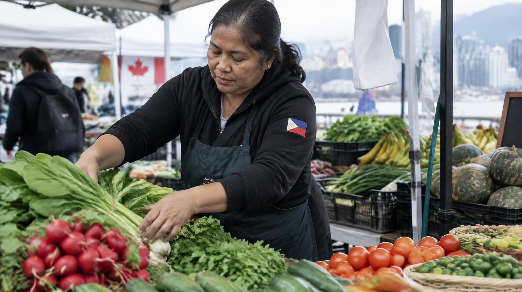 A street vendor arranging produce at an outdoor market