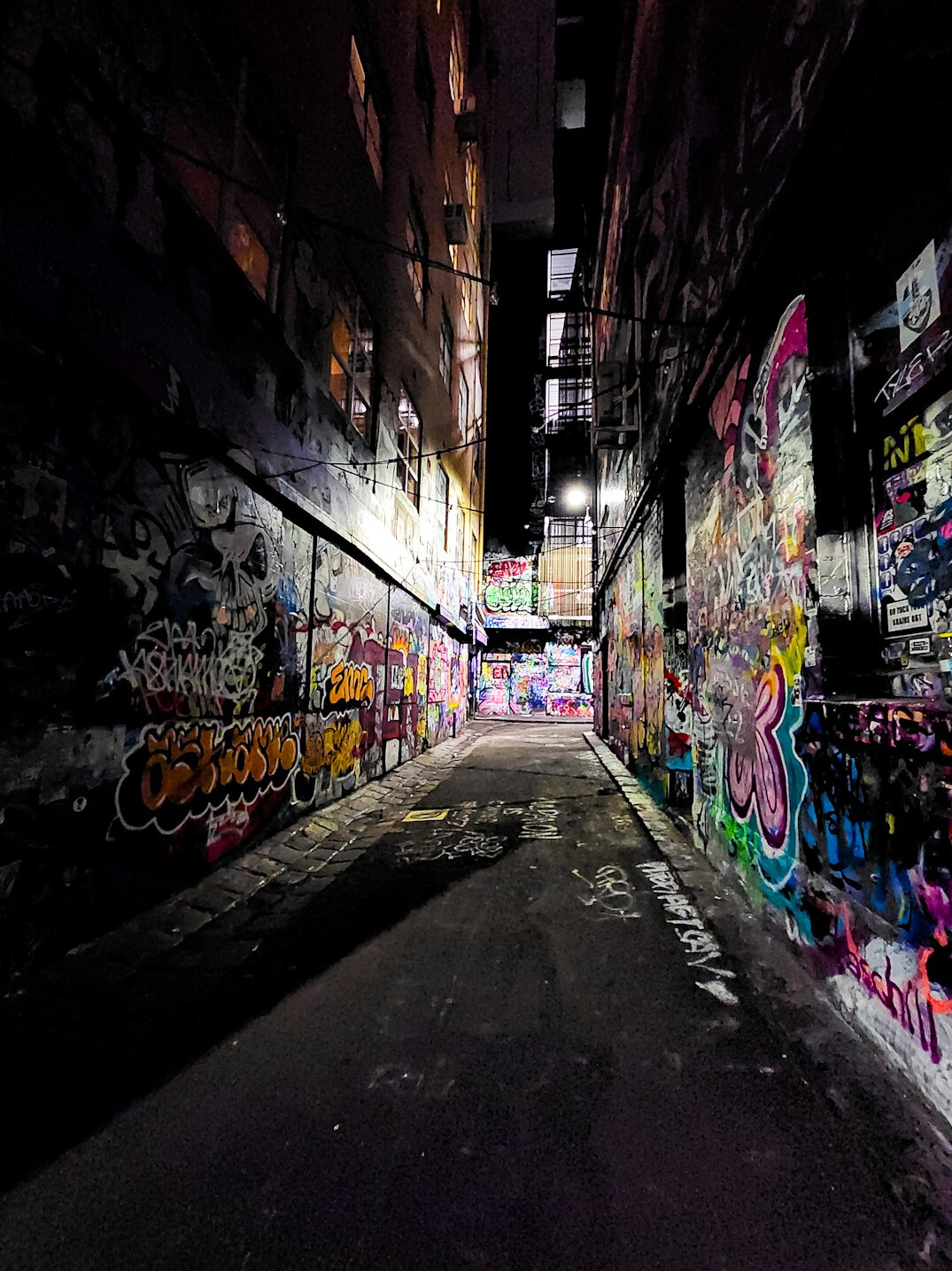 A photographer crouched photographing a graffiti covered alley wall